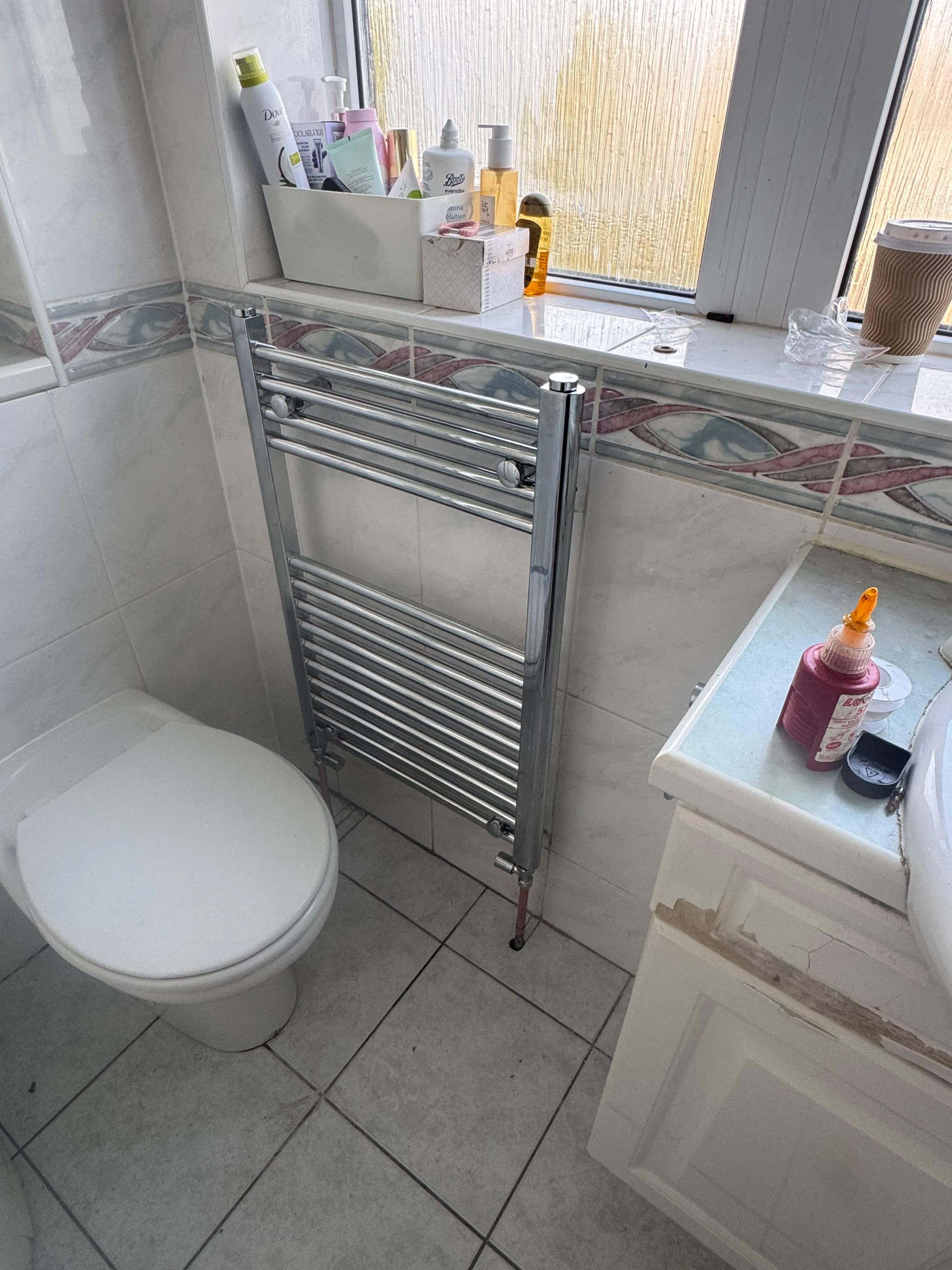 Chrome heated towel rail installation in bathroom