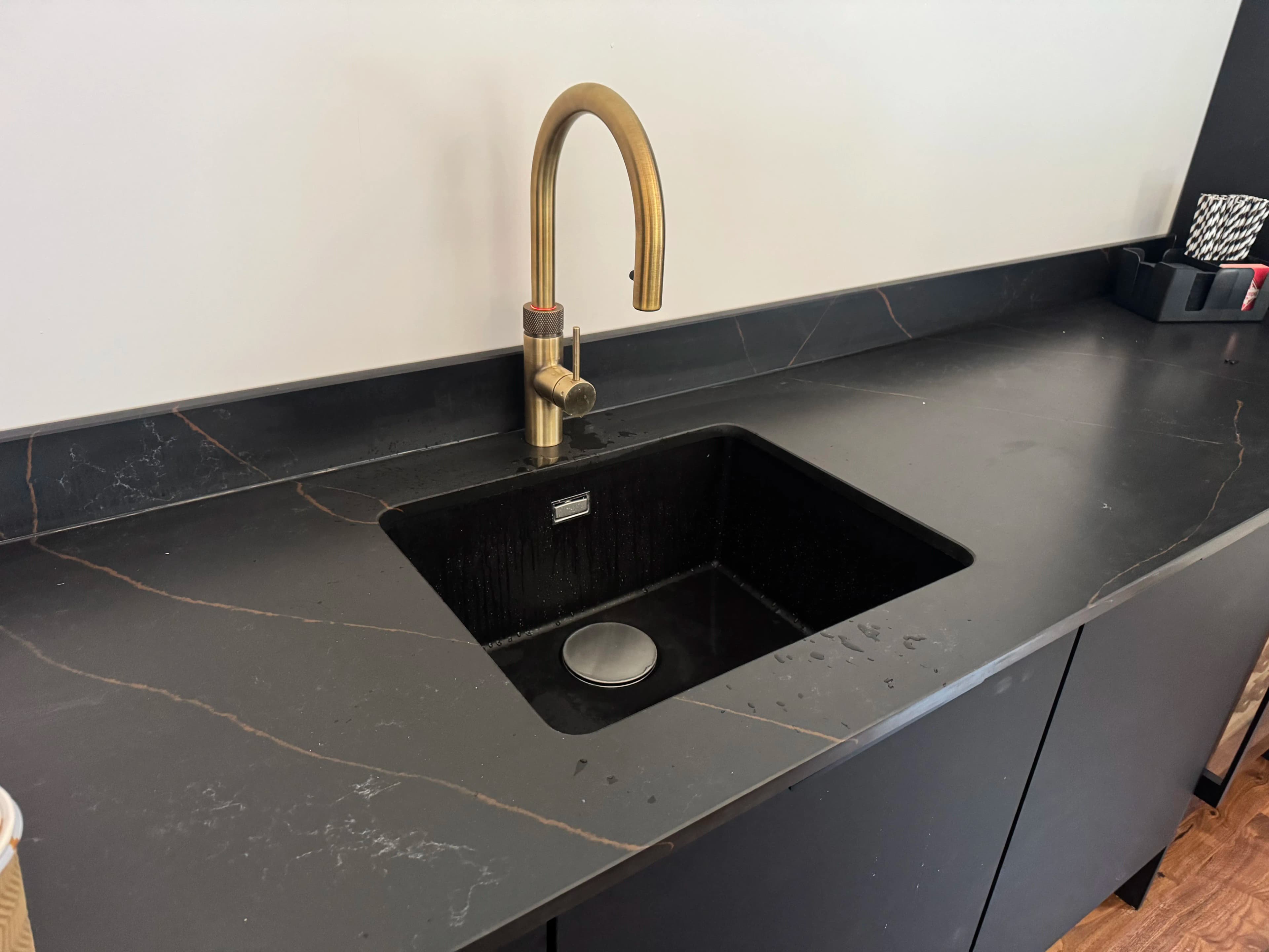 Black quartz worktop with brushed brass kitchen tap