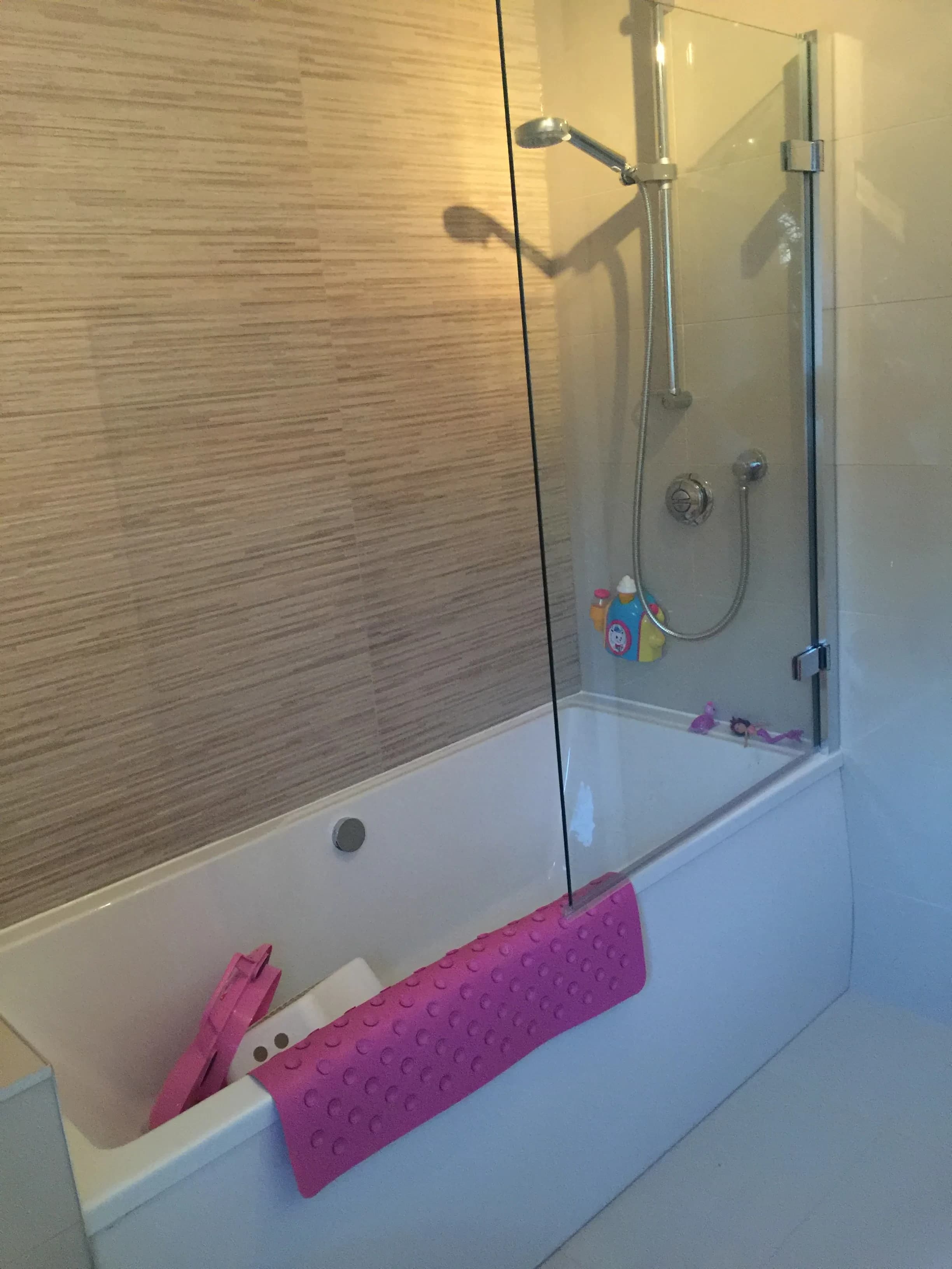 Bath with textured feature wall tiles and glass screen