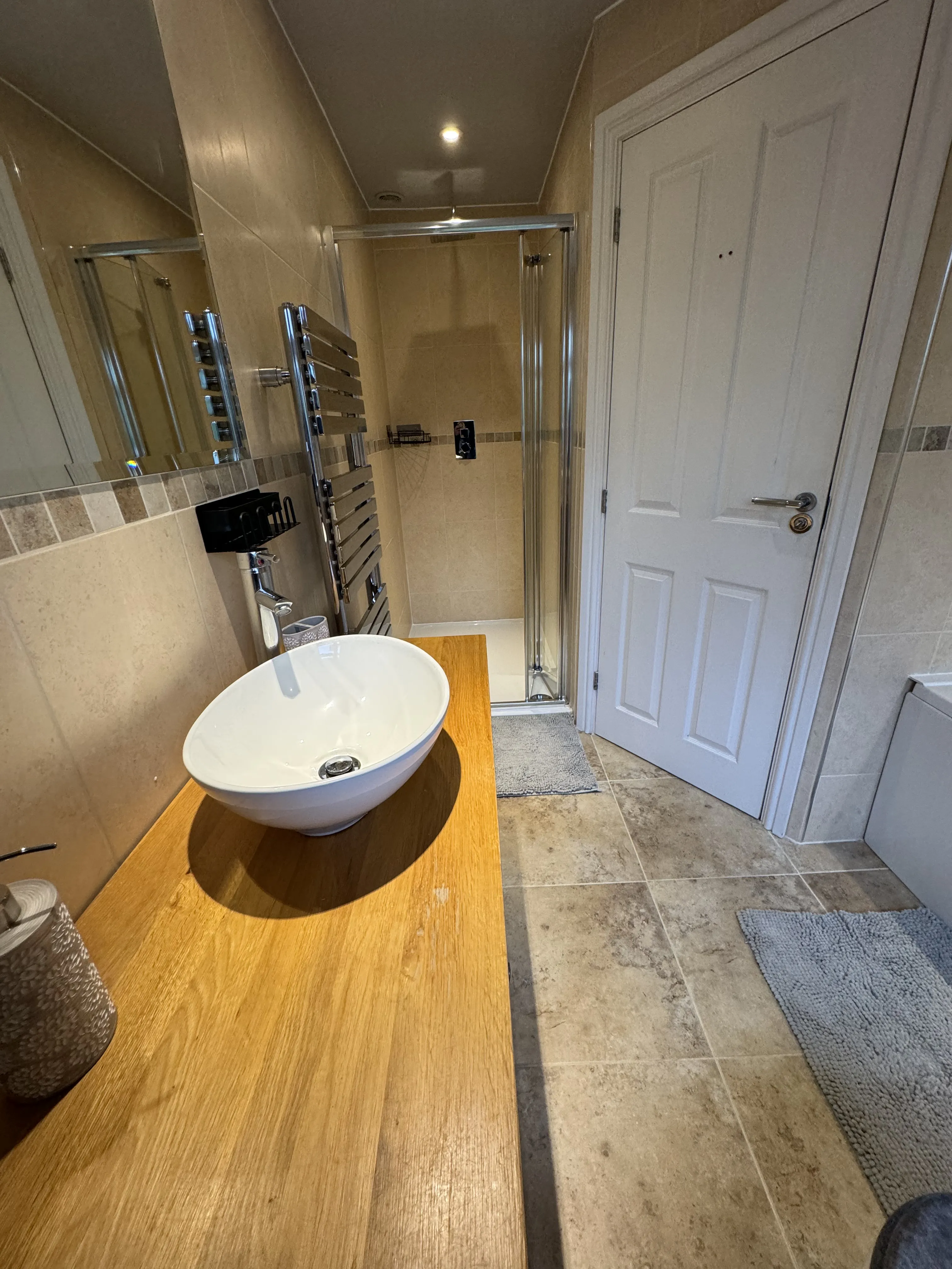 Vessel basin on oak countertop with shower enclosure