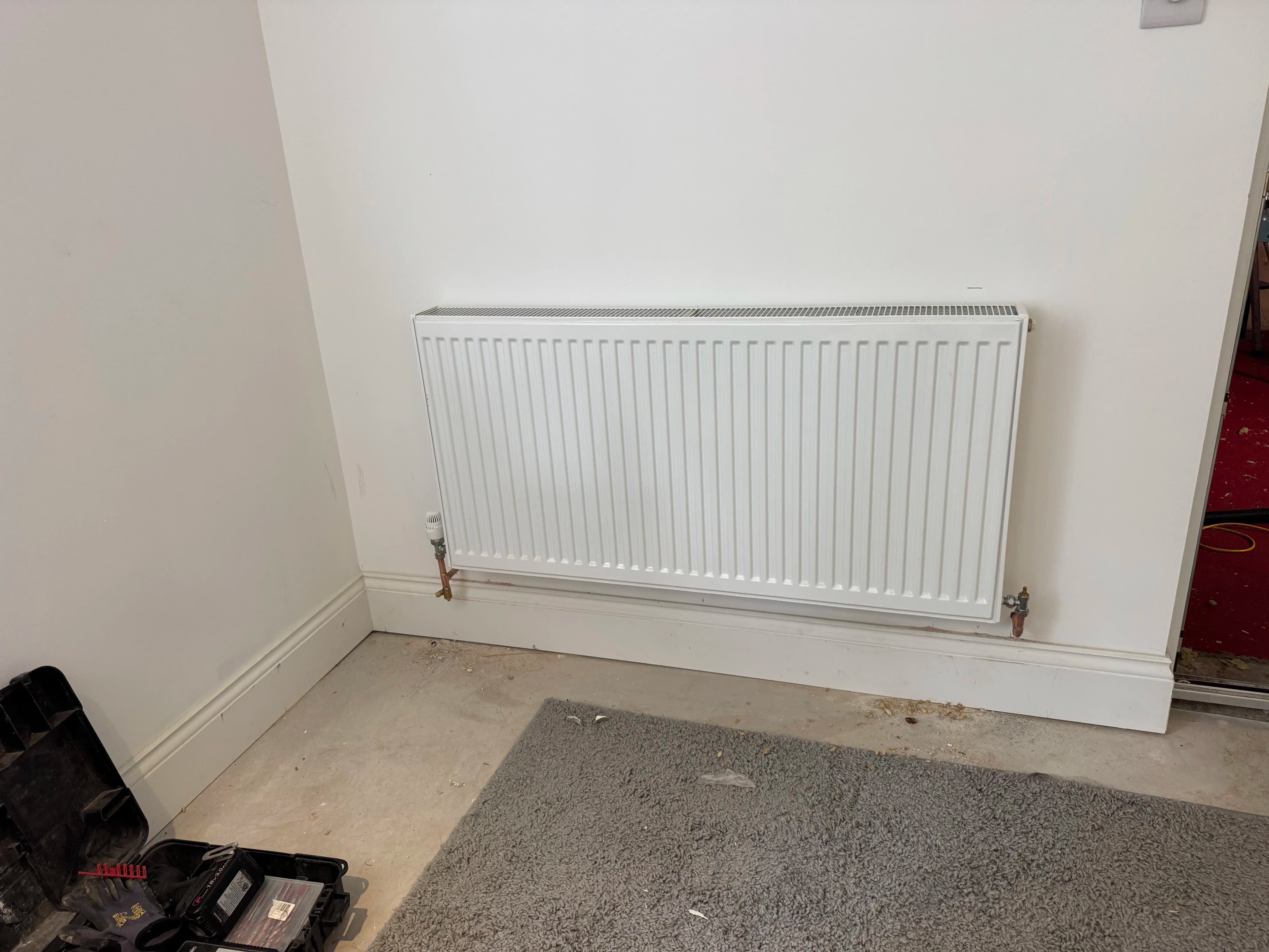 Panel radiator installation on freshly painted wall