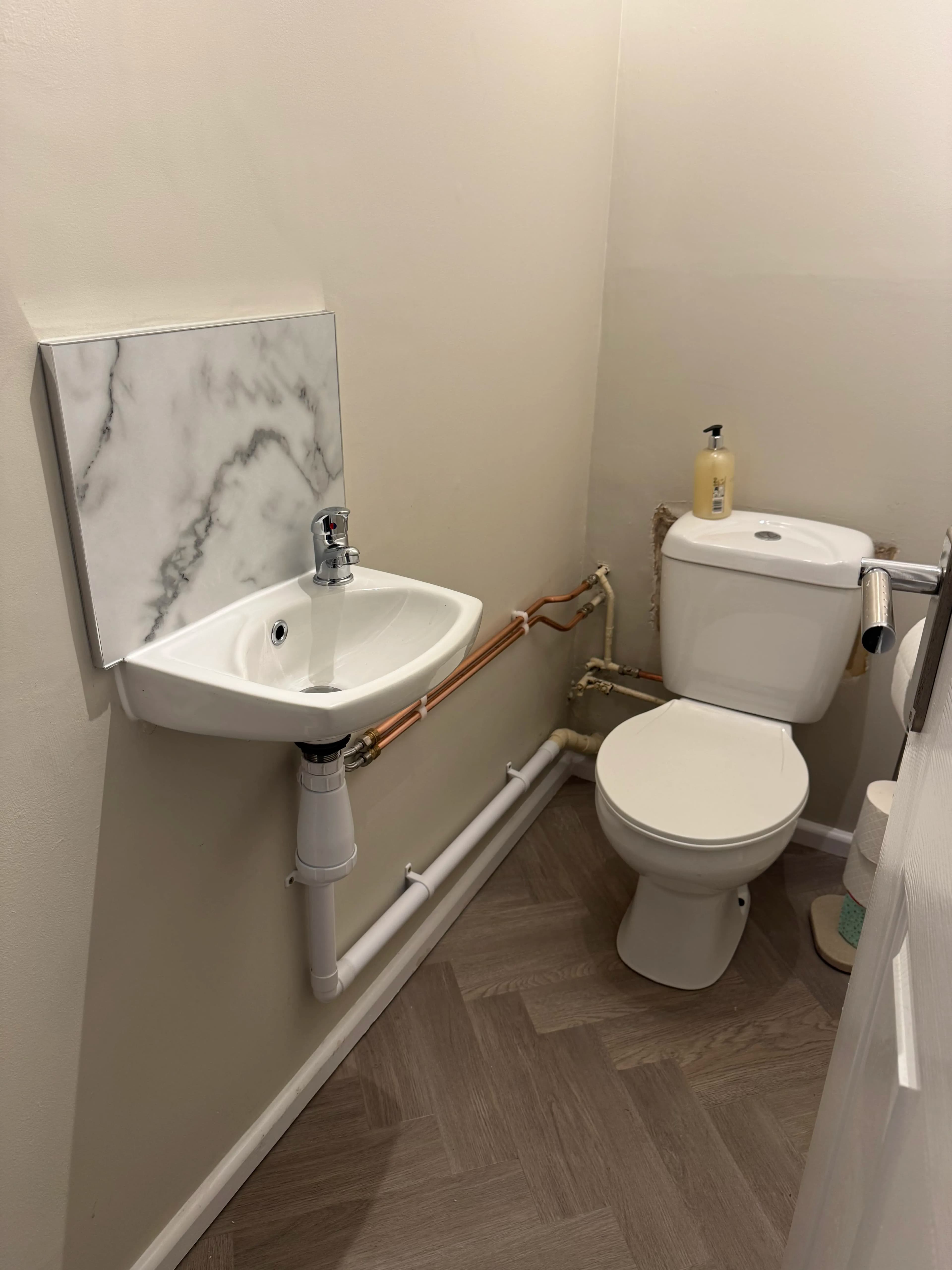 Cloakroom basin and toilet installation with herringbone flooring